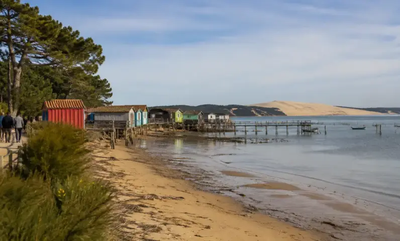 Cabanes ostréicoles du village de L'Herbe et Dune du Pilat en arrière-plan, sur le Bassin d'Arcachon