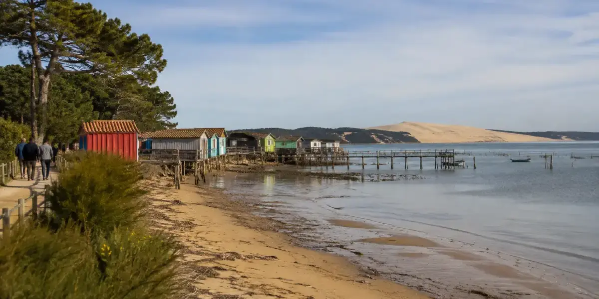 Cabanes ostréicoles du village de L'Herbe et Dune du Pilat en arrière-plan, sur le Bassin d'Arcachon